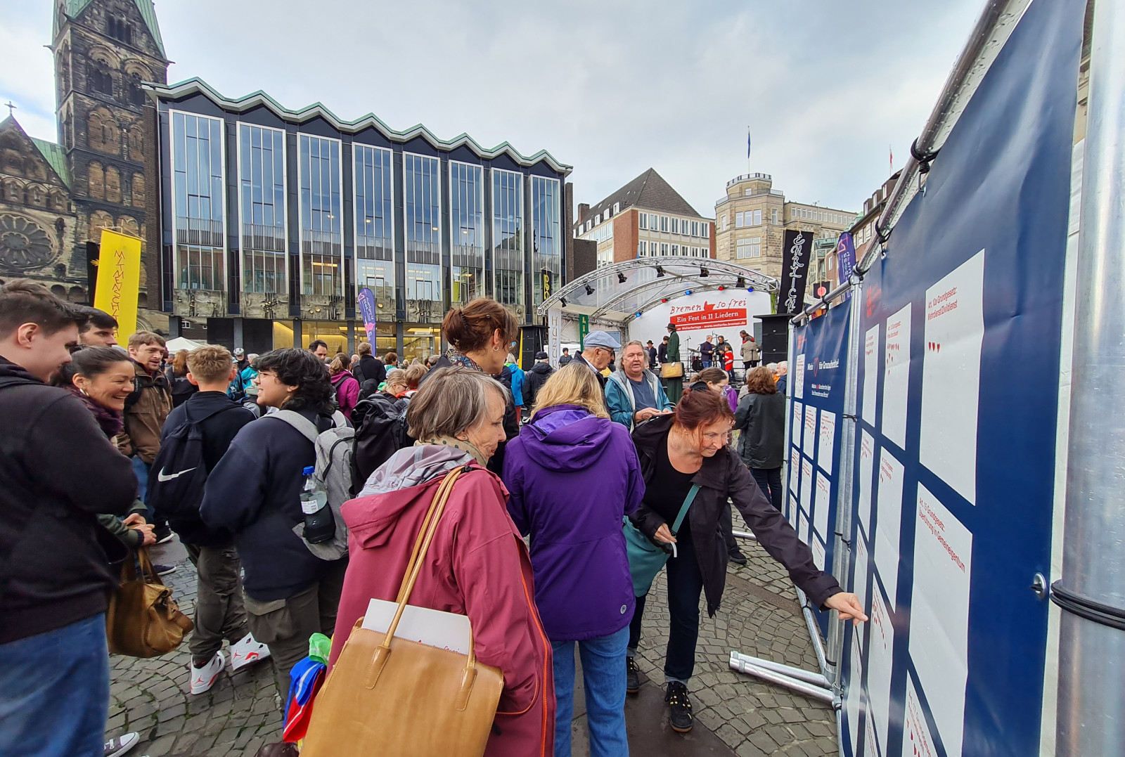 Auf dem Bild ist eine belebte Menschenmenge zu sehen, die sich vor den Stellwänden des Projektes "Mein Herz für Grundrechte" versammelt hat. Im Hintergrund ist die Bremische Bürgerschaft erkennbar.  