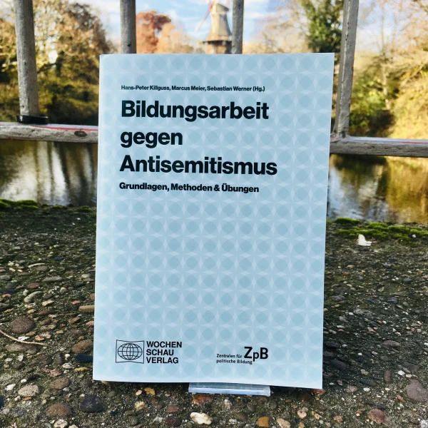 Ein Bild des Buches: "Bildungsarbeit gegen Antisemitismus"-Grundlagen, Methoden & Übungen, mit dem Hintergrund eines Stadtparks.  