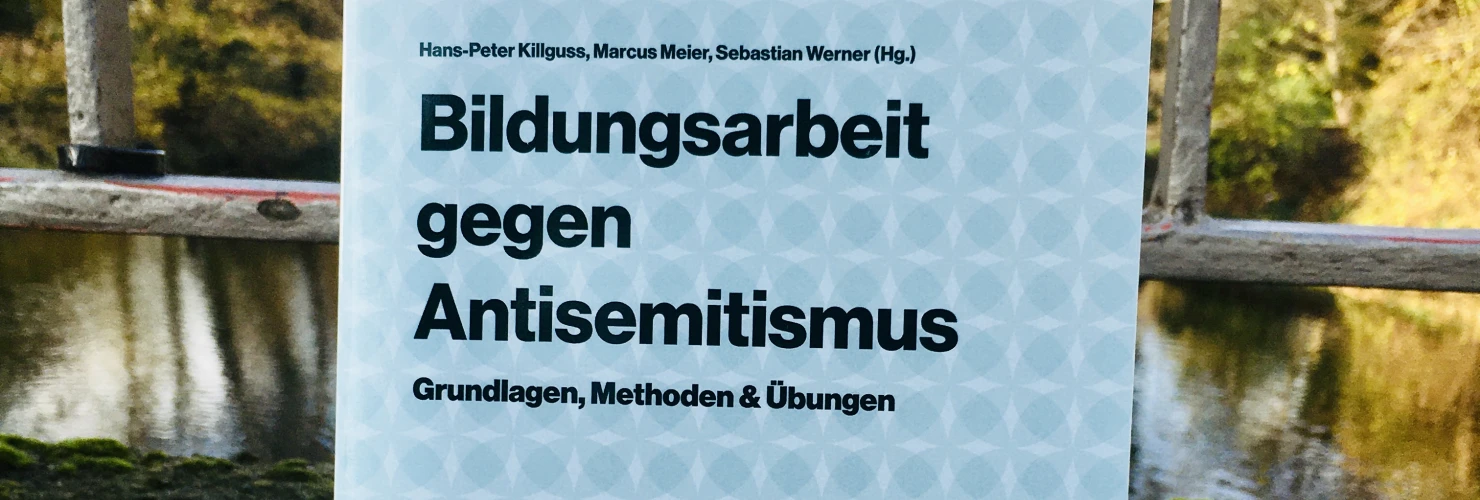 Ein Bild des Buches: "Bildungsarbeit gegen Antisemitismus"-Grundlagen, Methoden & Übungen, mit dem Hintergrund eines Stadtparks.  