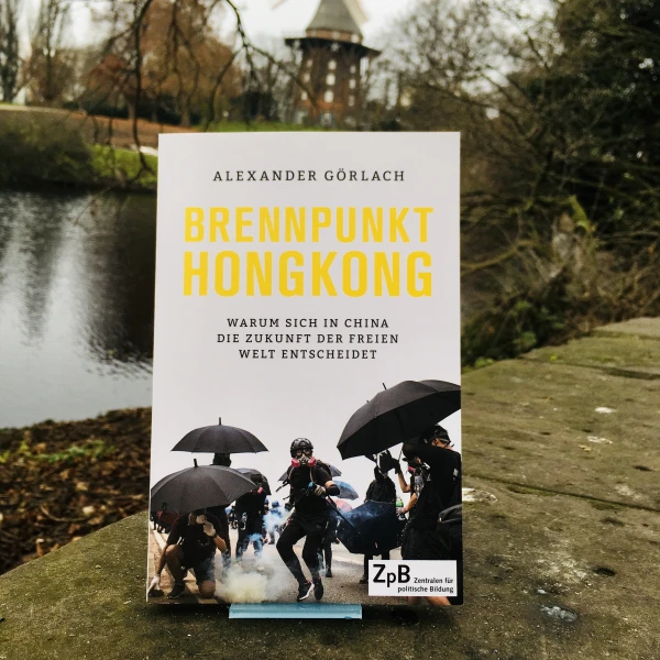 Ein Bild des Buches: "Brennpunkt Hongkong: Warum sich in China die Zukunft der freien Welt entscheidet" von Alexander Görlach mit dem Hintergrund der Mühle am Wall.  