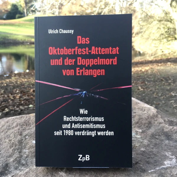 Ein Bild des Buches: " Das Oktoberfest-Attentat und der Doppelmord von Erlangen"-Wie Rechtsterrorismus und Antisemitismus seit 1980 verdrängt werden von Ulrich Chaussy, mit dem Hintergrund eines Stadtparks.  
