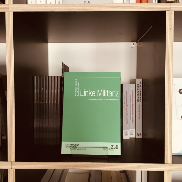 Ein Bild des Buches: "Linke Militanz"-Pädagogische Arbeit in Theorie und Praxis, mit dem Hintergrund von Büchern.  