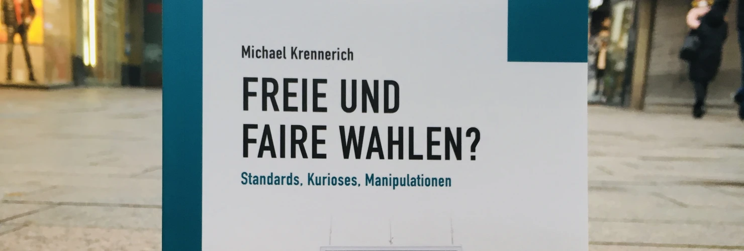 Ein Bild des Buches: "Freie und Faire Wahlen?"-Standards, Kurioses, Manipulationen von Michael Krennerich, mit dem Hintergrund einer städtischen Straße.  
