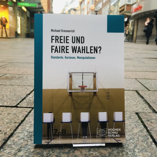 Ein Bild des Buches: "Freie und Faire Wahlen?"-Standards, Kurioses, Manipulationen von Michael Krennerich, mit dem Hintergrund einer städtischen Straße.  