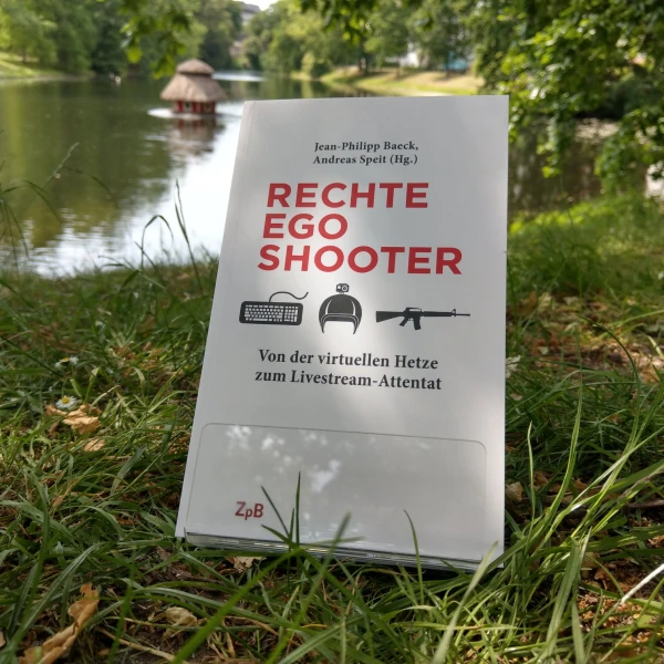 Ein Bild des Buches: "Rechte Egoshooter"- Von der virtuellen Hetze zum Livestream-Attentat, von Andreas Speit und Jean-Philipp Baeck, mit dem Hintergrund des Sees.  