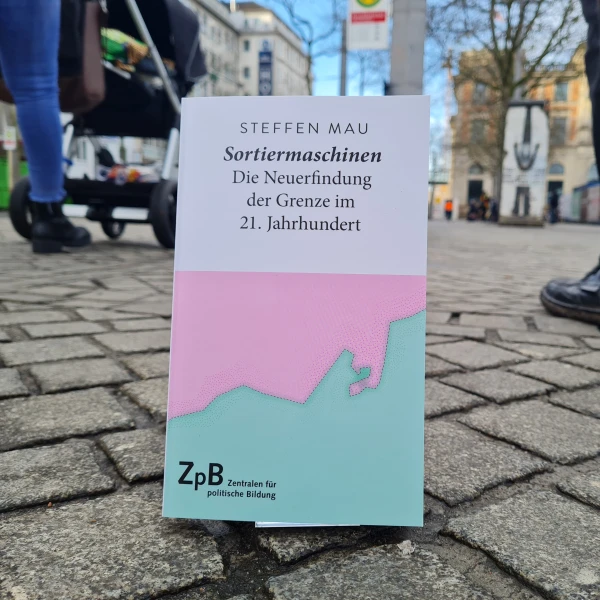 Ein Bild des Buches "Sortiermaschinen-Die Neuerfindung der Grenze im 21. Jahrhundert" von Steffen Mau mit einem Hintergrund einer städtischen Straße.  