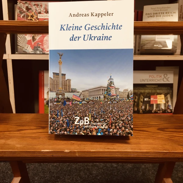 Das Buchcover von "Kleine Geschichte der Ukraine" mit einem Foto einer Demonstration von Tausenden von Menschen, die auf dem Hauptplatz von Kiew, dem "Maidan", stehen und verschiedene Fahnen schwenken.   