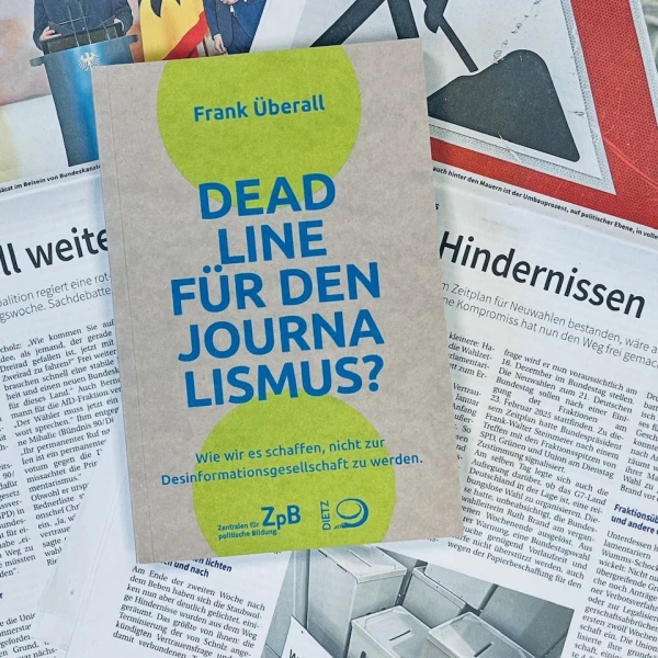 Auf dem Bild liegt ein hellgrün markiertes Buch in der Mitte mehrerer aufgeschlagener Zeitungsseiten, die in deutscher Sprache bedruckt sind. Das Buch trägt den Titel "DEADLINE FÜR DEN JOURNALISMUS?" und den Untertitel "Wie wir es schaffen, nicht zur Desinformationsgesellschaft zu werden." Das Buch ist beige, während die Schrift blau ist.  