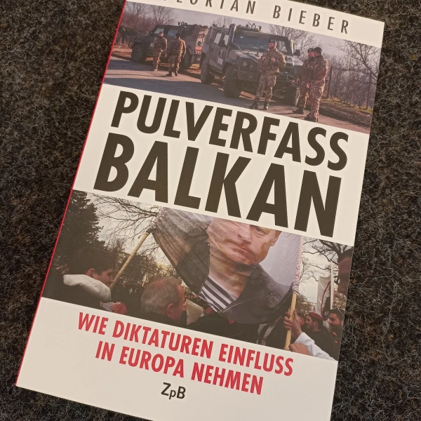 Das Buchcover von "Pulverfass Balkan - Wie Diktaturen Einfluss in Europa nehmen" von Florian Bieber. Darauf abgebildet sind zwei Fotos. Eines zeigt ein Militär-Konvoi ein anderer demonstrierende Menschen.    
