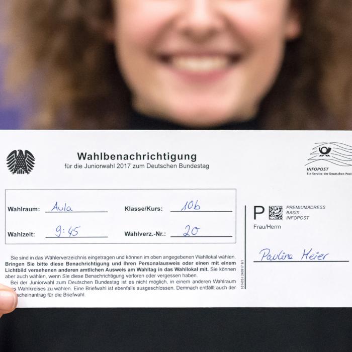 Eine Person zeigt einen Wahlbenachrichtigung für die Juniorwahl 2017 zum Deutschen Bundestag.