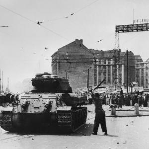 Schwarz-Weiß-Foto. Der Mann in der Demonstration schägt mit einem Stock auf einer Panzer.