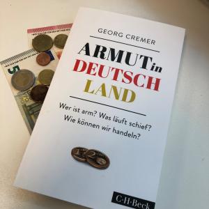 Buchcover von "Armut in Deutschland"- Wer ist arm? Was läuft schief? Wie können wir handeln? von Georg Cremer, mit dem Hintergrund des Bargeldes.