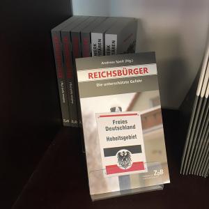 Ein Bild des Buches: "Reichsbürger"-Die unterschätzte Gefahr von Andreas Speit, mit dem Hintergrund der Bücher.