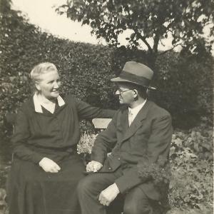 Frieda Kreikmeyer sitzt vor ihrem Ehemann im Garten.