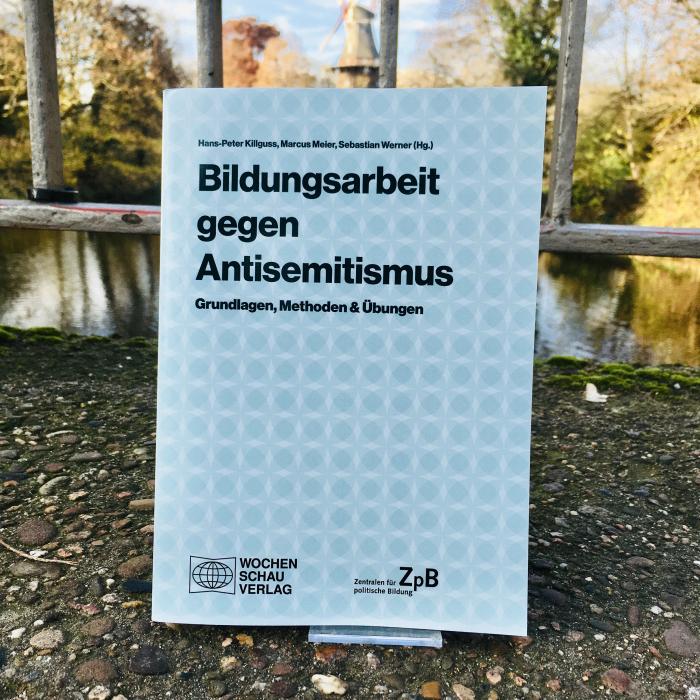 Ein Bild des Buches: "Bildungsarbeit gegen Antisemitismus"-Grundlagen, Methoden & Übungen, mit dem Hintergrund eines Stadtparks.