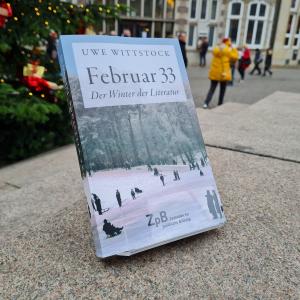 Ein Bild des Buches "Februar 33-Der Winter der Literatur" von Uwe Wittstock mit dem Hintergrund eines Weihnachtsbaums auf dem Stadtplatz.