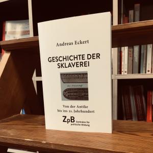 Ein Bild des Buches "Geschichte der Sklaverei. Von der Antike bis ins 21. Jahrhundert" von Andreas Eckert mit dem Hintergrund aus Bücherregalen. 
