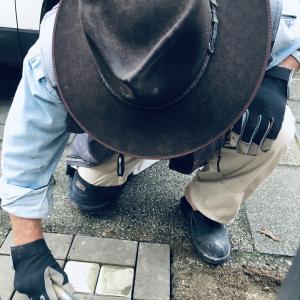 Eine Person mit einem schwarzen Hut verlegt einen Stolperstein. 