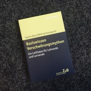 Zu sehen ist ein gelb-schwarzes Buchcover: "Basiswissen Verschwörungsmythen. Eine Handreichung für Lehrende und Lernende". 